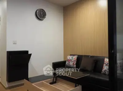 Modern living room with stylish black sofa and wooden accents, perfect for cozy relaxation.