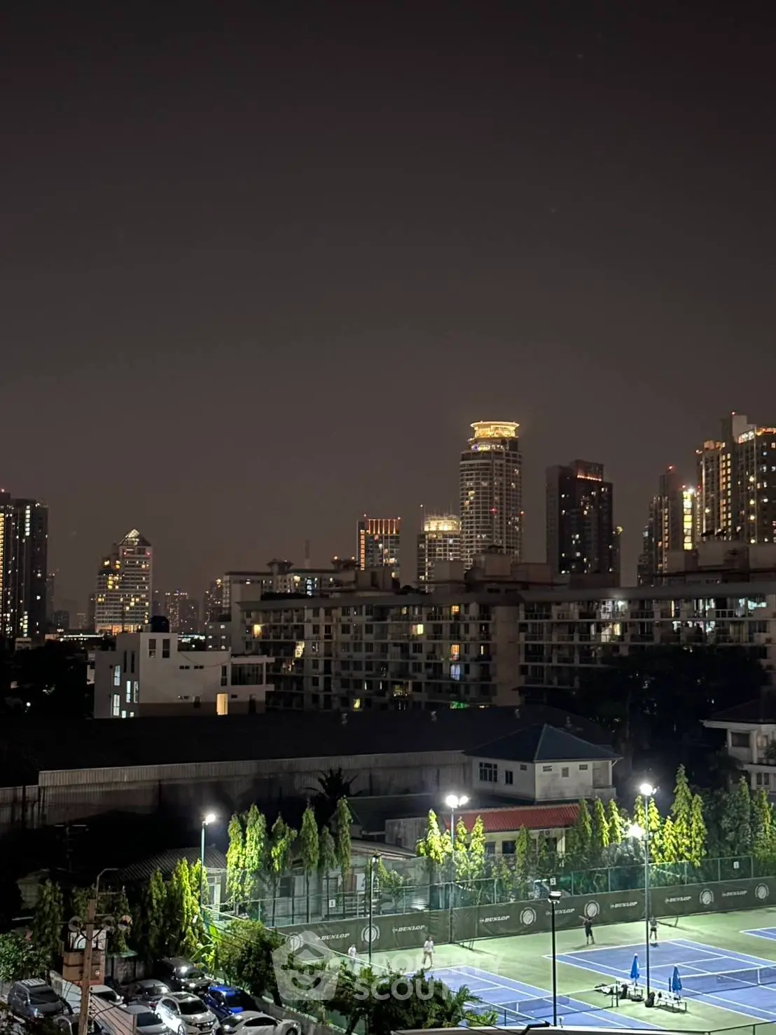 Stunning cityscape view with illuminated tennis courts and skyline at night.