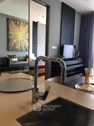 Modern open-layout kitchen with sleek faucet and view into stylish living room.