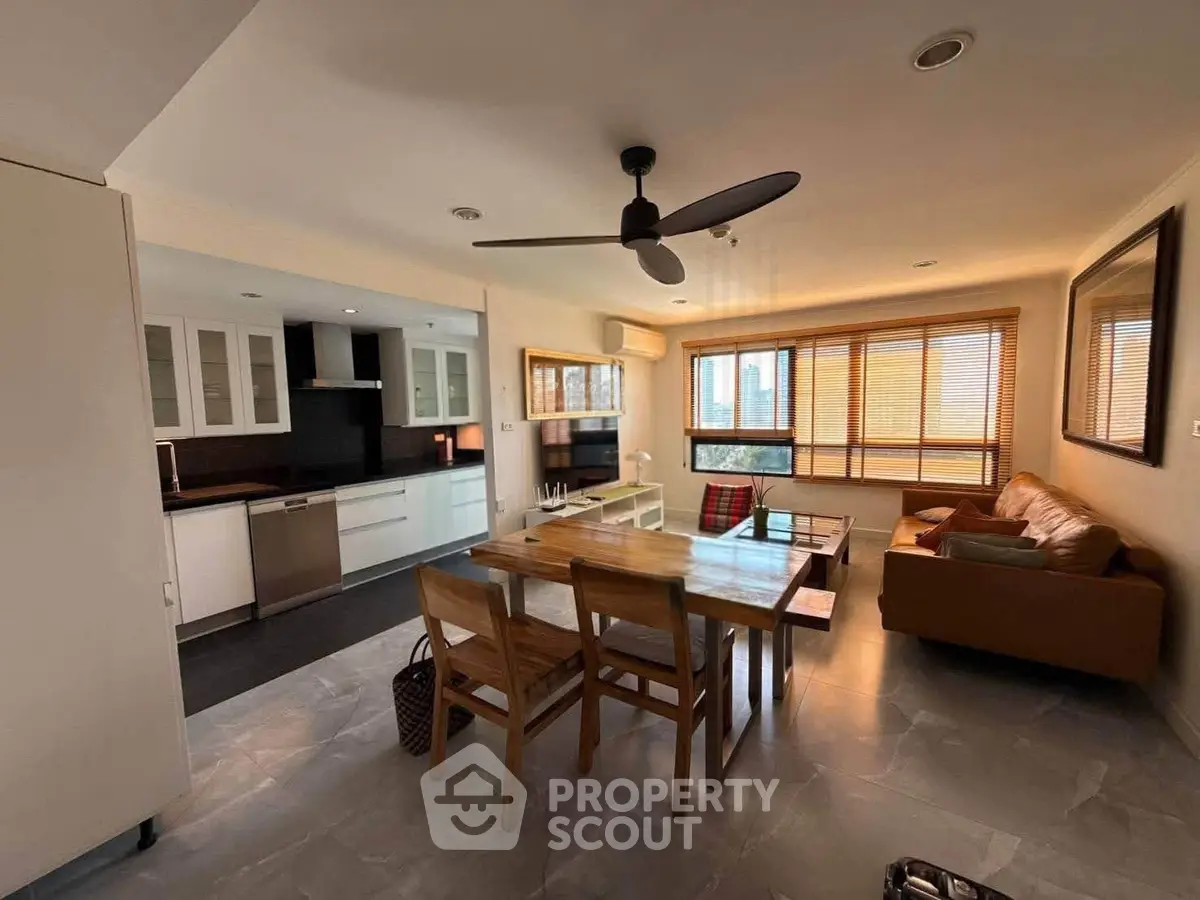 Spacious open-plan living room with modern kitchen and dining area, featuring natural light and stylish furnishings.