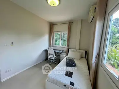 Cozy bedroom with single bed, study desk, and lush garden view