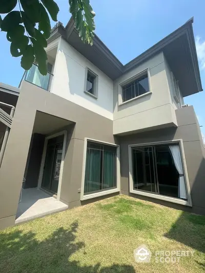 Modern two-story house with large windows and lush green lawn