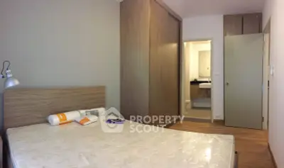 Modern bedroom with ensuite bathroom and wooden wardrobe in a stylish apartment.