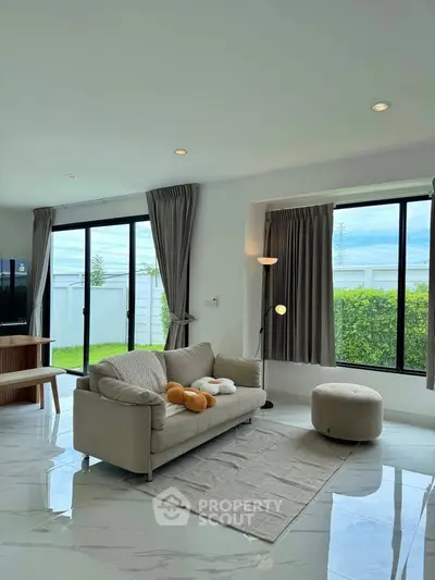 Spacious living room with modern decor and large windows offering garden views.