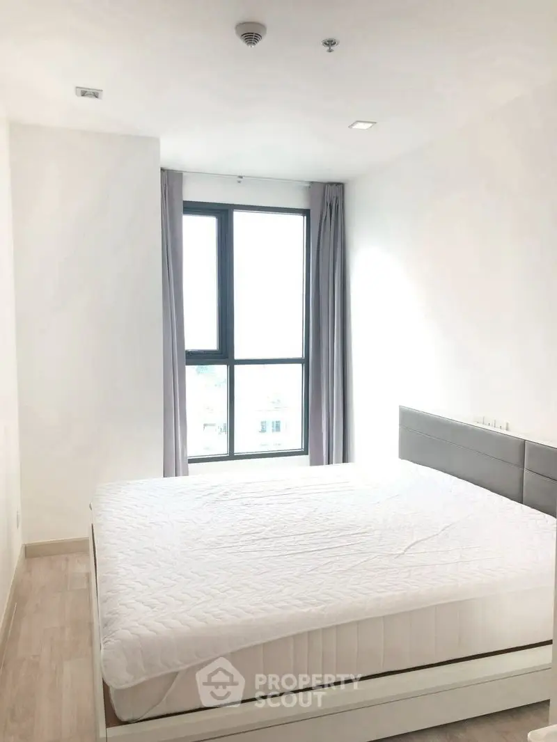 Bright bedroom with large window and modern bed in minimalist style.