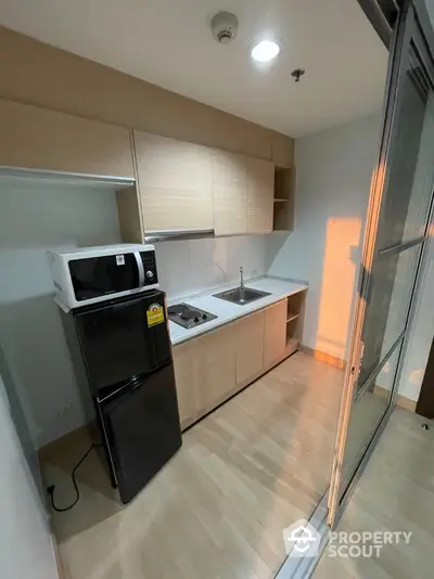 Modern compact kitchen with sleek cabinets and appliances in a cozy apartment setting.