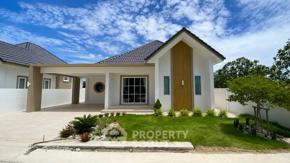 Charming modern house with manicured lawn and spacious driveway under a clear blue sky.