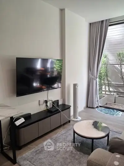 Modern living room with wall-mounted TV and stylish decor, featuring a cozy balcony view.