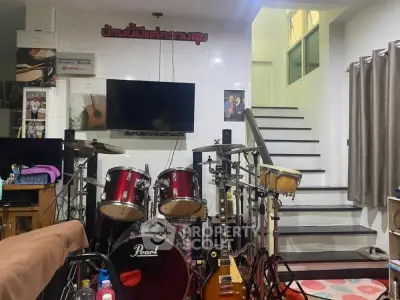 Cozy music-themed living area with drum set and guitar, perfect for musicians.