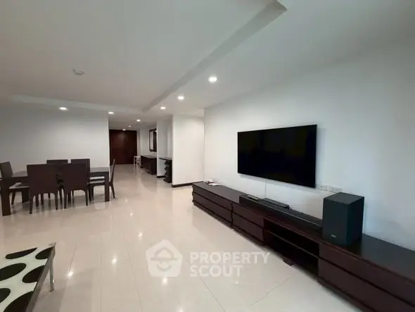 Spacious modern living room with sleek furniture and large TV, perfect for entertainment.