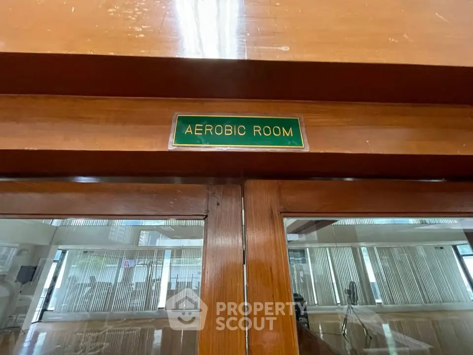 Spacious aerobic room with wooden accents and glass doors in a modern fitness facility.