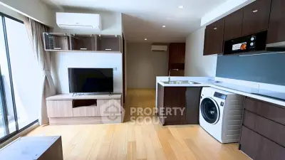 Modern living room with open kitchen, featuring sleek appliances and wooden flooring, ideal for urban living.