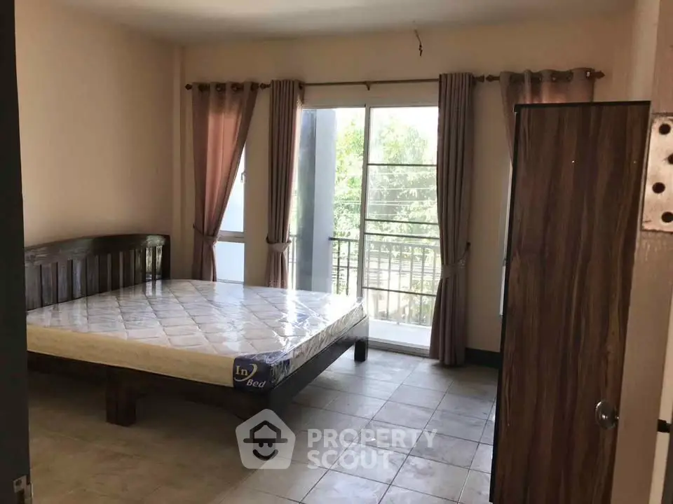 Spacious bedroom with large window and balcony access in modern apartment.