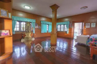 Spacious living room with wooden floors and large windows in a cozy home.