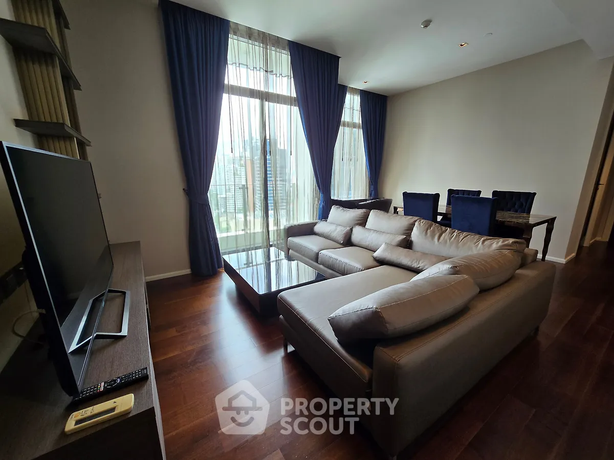 Luxurious living room with modern furniture and city view, featuring elegant curtains and hardwood flooring.