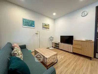 Modern living room with stylish furniture and wooden flooring, featuring a cozy sofa and sleek TV setup.