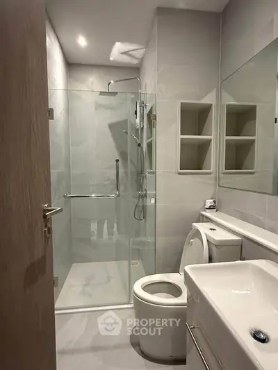 Modern bathroom with glass shower and sleek fixtures in a contemporary apartment.