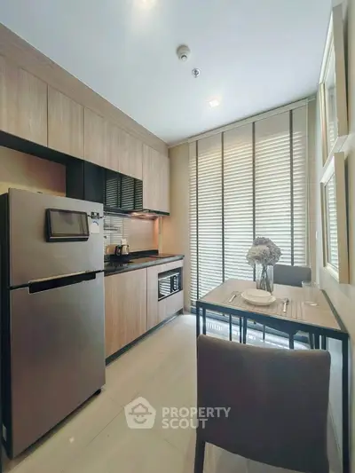 Modern kitchen with sleek cabinetry and dining area, featuring stainless steel appliances and natural light.