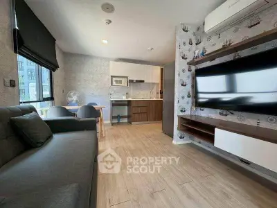 Modern living room with stylish decor and open kitchen layout, featuring a large TV and comfortable seating.