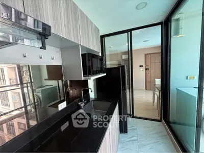Modern kitchen with sleek black countertops and glass sliding doors in a stylish apartment.