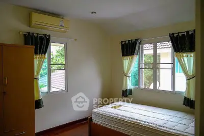 Cozy bedroom with natural light, featuring air conditioning and wooden flooring.