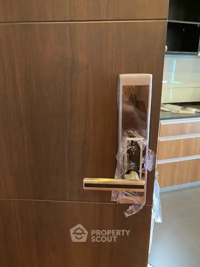 Modern apartment entrance with sleek electronic door lock and stylish kitchen view.