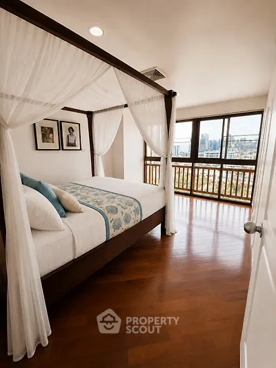 Luxurious bedroom with canopy bed and stunning city view from large windows.