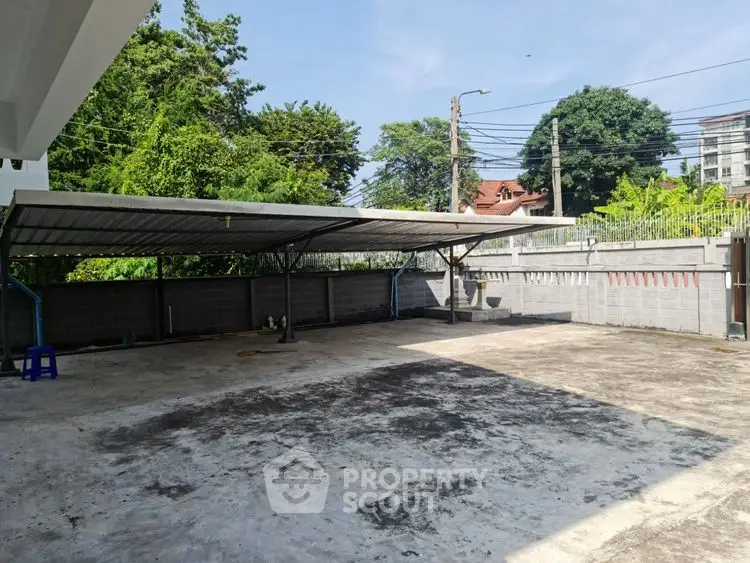 Spacious outdoor parking area with covered section and surrounding greenery