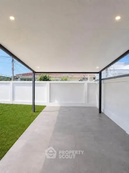 Modern covered patio with sleek design and green lawn, perfect for outdoor relaxation.
