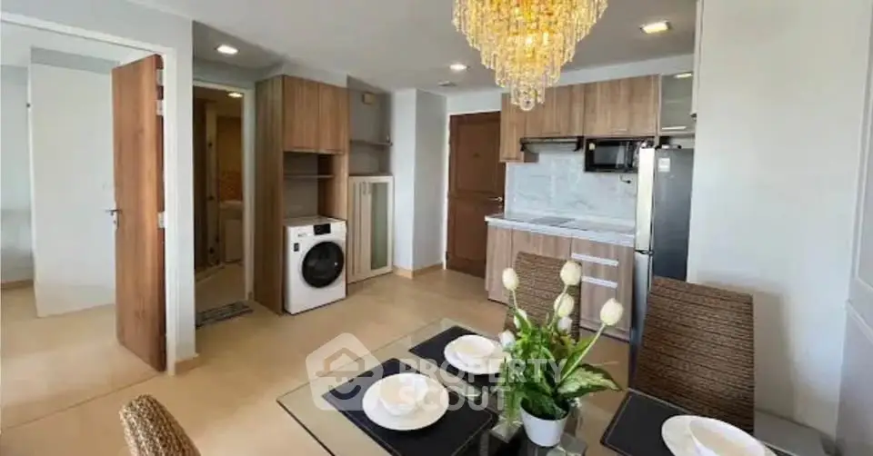 Modern kitchen and dining area with elegant chandelier and built-in appliances in a stylish apartment.