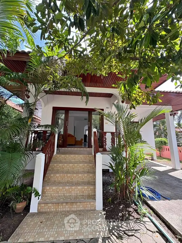 Charming tropical home entrance with lush greenery and inviting steps