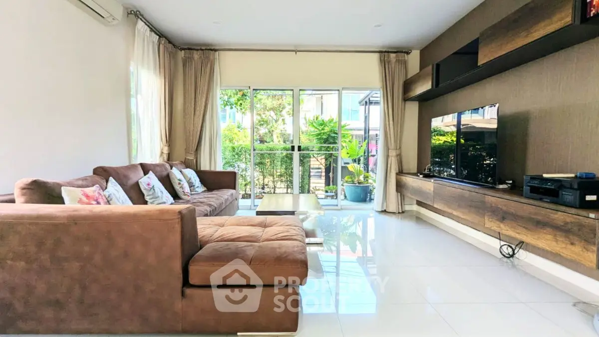 Spacious living room with modern decor and large windows overlooking garden.