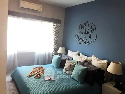 Cozy bedroom with blue accent wall and stylish decor, featuring ample natural light and modern furnishings.
