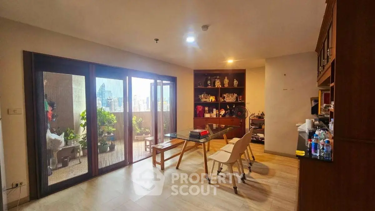 Spacious living room with balcony and city view, featuring elegant wooden furniture and ample natural light.