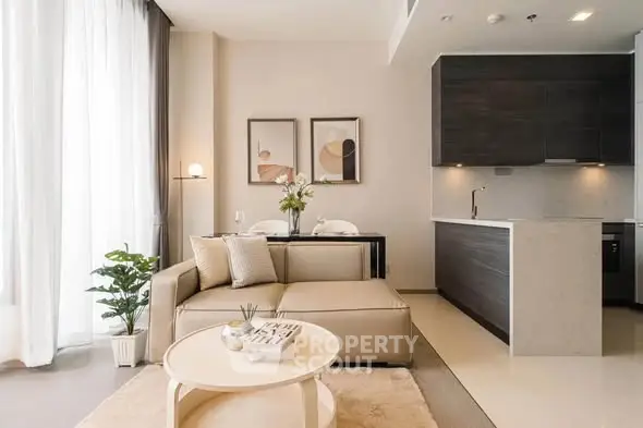 Modern living room with open kitchen, stylish decor, and natural light.
