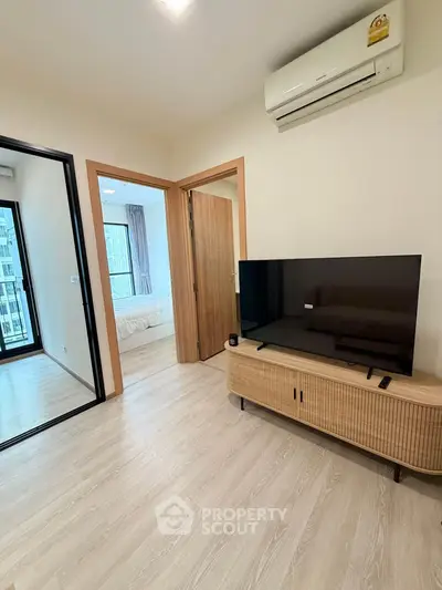 Modern living room with sleek TV setup and view into cozy bedroom