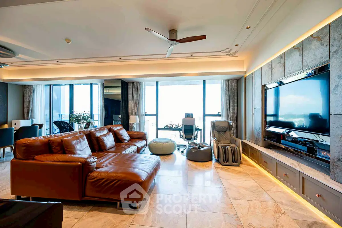 Luxurious modern living room with leather sofa and large TV, featuring panoramic windows and elegant decor.