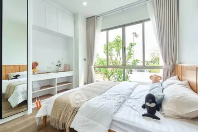 Bright and cozy bedroom with large window and modern decor, perfect for relaxation and comfort.