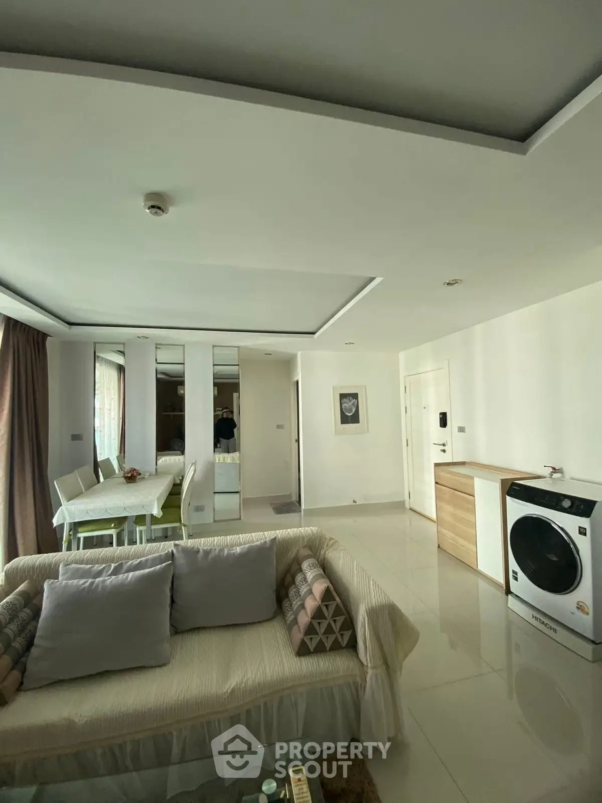 Modern living room with washing machine and dining area in open layout apartment.