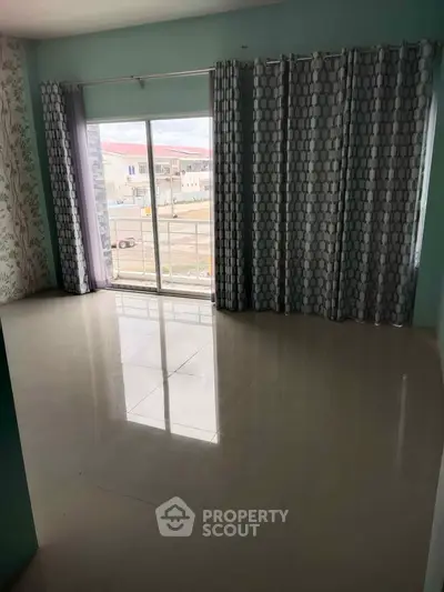 Spacious living room with large windows and modern curtains, offering ample natural light and a view of the outdoors.