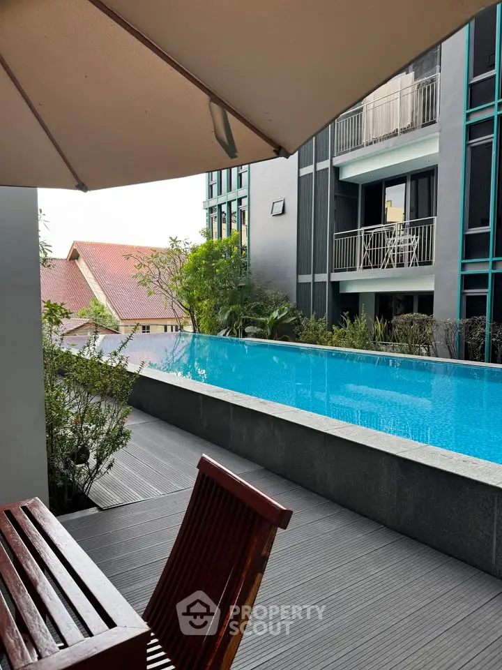 Luxurious poolside view with modern building and balcony, perfect for relaxation.