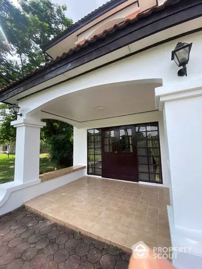 Charming house entrance with tiled porch and elegant archway, perfect for welcoming guests.