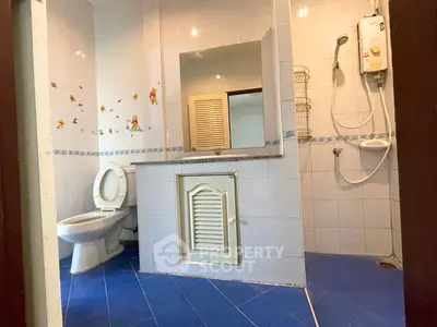Spacious bathroom with modern fixtures and blue tile flooring, featuring a large mirror and shower area.