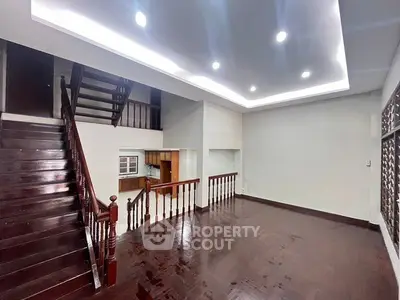 Spacious open-plan living area with elegant wooden staircase and modern lighting.
