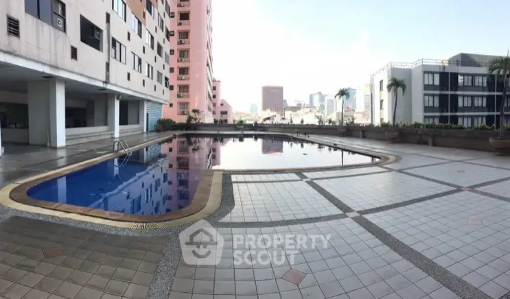 Spacious rooftop pool area with city skyline views, perfect for relaxation and leisure in urban living.