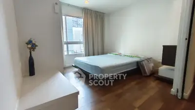 Modern bedroom with wooden flooring and large window in a high-rise apartment.