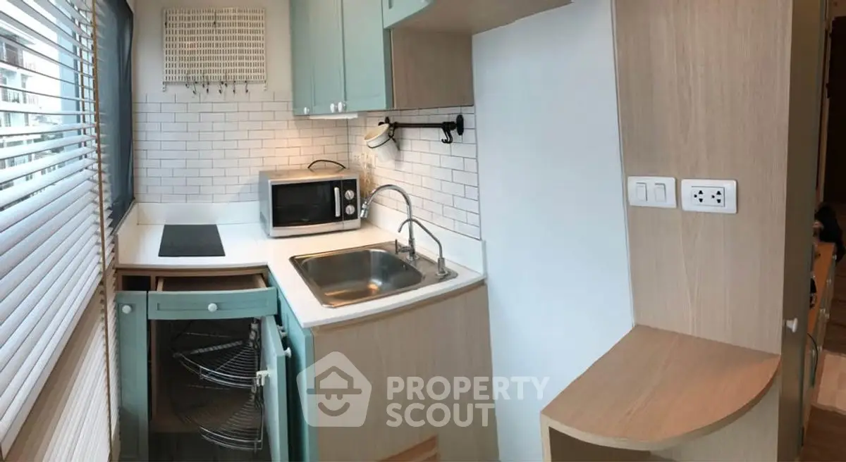 Modern compact kitchen with sleek cabinetry and built-in appliances, featuring a stylish backsplash and ample natural light.