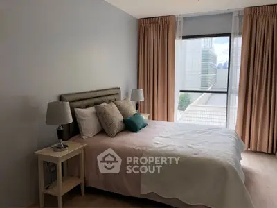 Cozy bedroom with modern decor and large window offering city view.