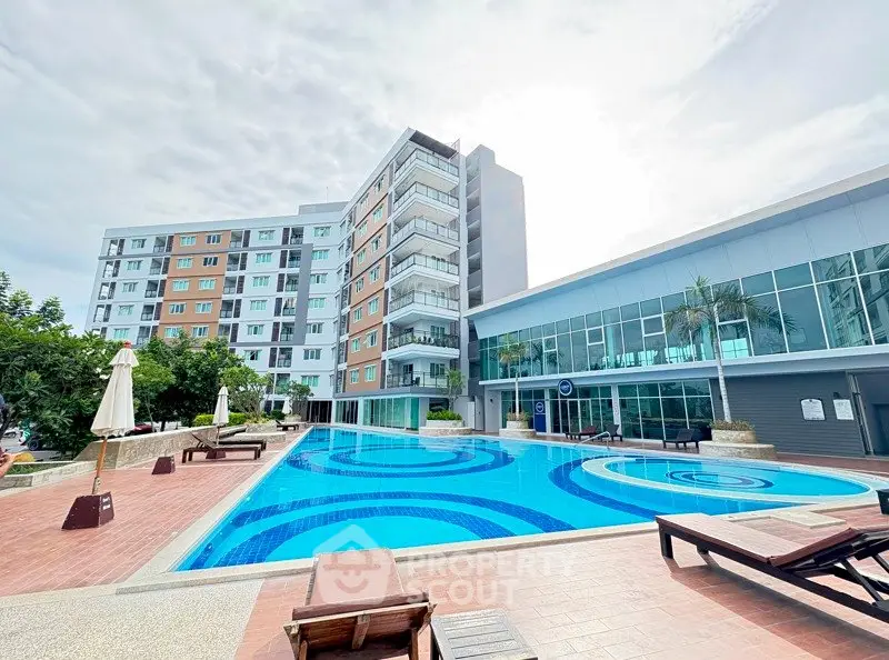 Modern apartment complex with a stunning outdoor pool and sun loungers.