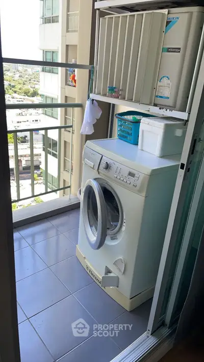 Compact balcony with washing machine and city view, ideal for urban living.